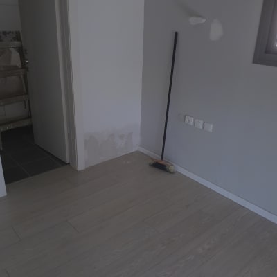 קיר צבוע עם תיקוני צבע ומטאטא נשען עליו