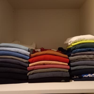 חולצות מקופלות בצבעים שונים על מדף בארון