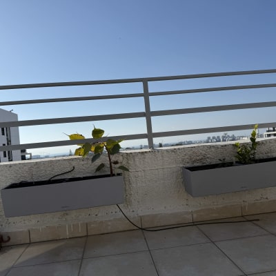 שני אדניות אפורות תלויות על מעקה מרפסת