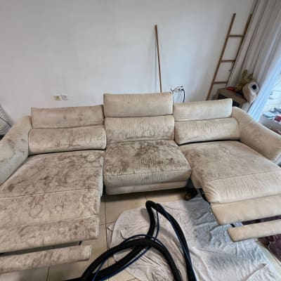 ספה בהירה עם כתמים, צינור שואב אבק על הרצפה