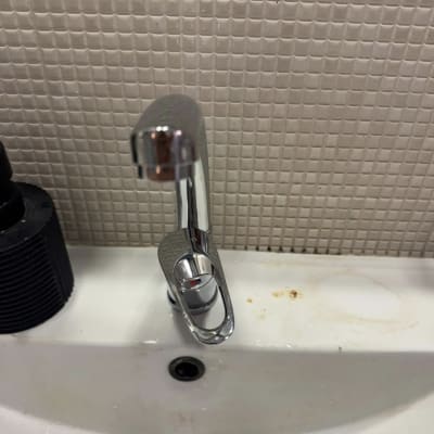 ברז כיור עם ידית מתכת על רקע אריחים