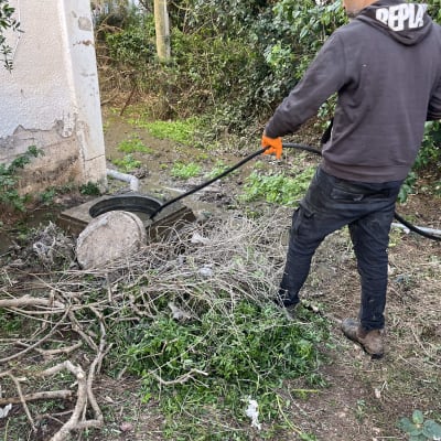 אדם עם כפפות כתומות מחזיק צינור ליד מכסה ביוב