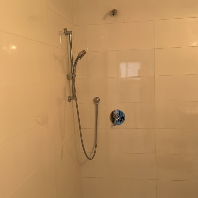 מקלחת עם אריחים לבנים וראש מקלחת
