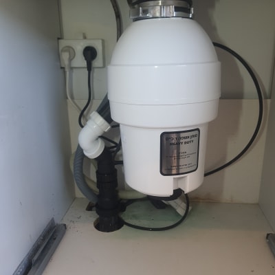 מטחנת אשפה מתחת לכיור עם צינורות חיבור