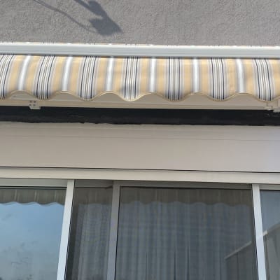 סוכך פסים בצבעים חום ולבן מעל חלון