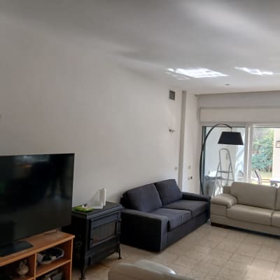 סלון עם ספה, טלוויזיה וסולם ליד חלון גדול