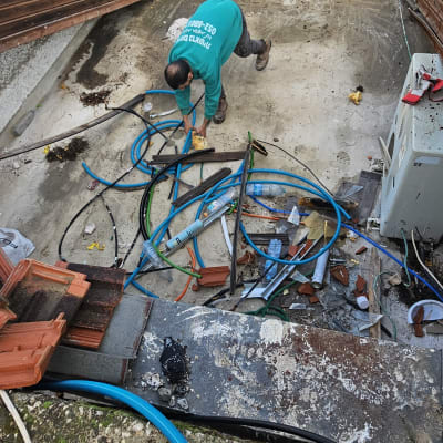 אדם עובד על גג עם צינורות וכלים לאיטום