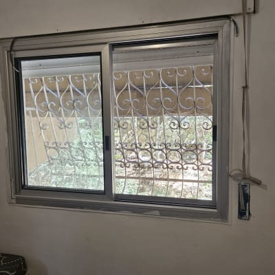 חלון עם תריסים ומעקה ברזל