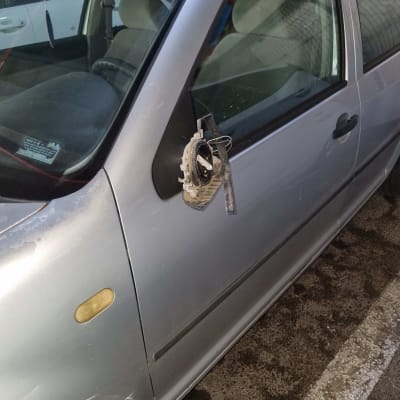 מראה צד שבורה תלויה על דלת רכב כסוף