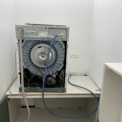 מכונת כביסה פתוחה עם חיבורים חשמליים וצינורות