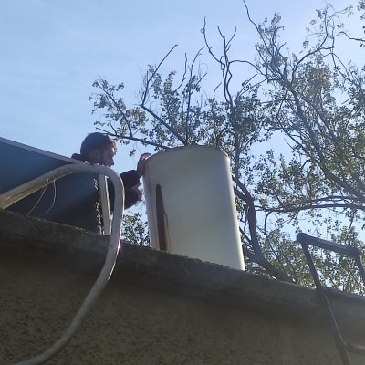 אדם מתקין דוד שמש על גג עם צינורות