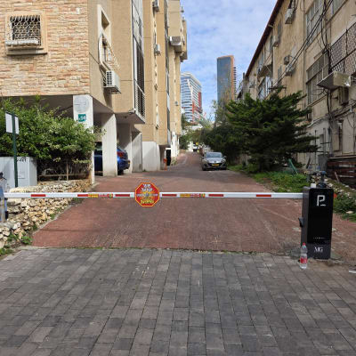 שער חשמלי בכניסה לחניון עם שלט ושם חברה