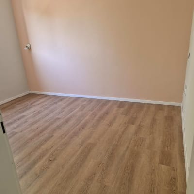 רצפת פרקט עץ בחדר ריק עם קיר ורוד