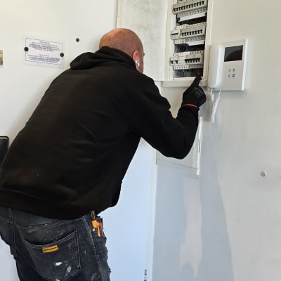 חשמלאי עובד על לוח חשמל פתוח עם כלים