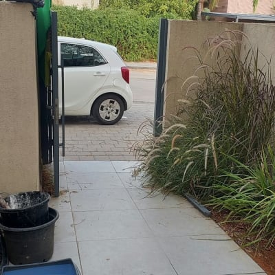 שער כניסה ממתכת מותקן בפתחה של חצר בית פרטי