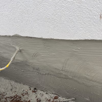 חומר איטום אפור על קיר עם צינור חשמל