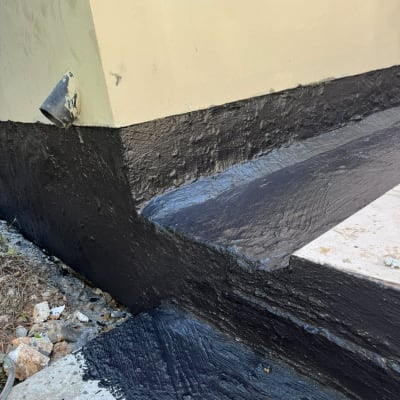 יישומי חומר איטום ביטומני שחור בחיבור בין קיר חיצוני לרצפה ומדרגה