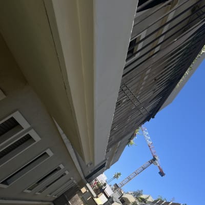 עבודות גובה על מרפסת בניין עם מנוף ברקע