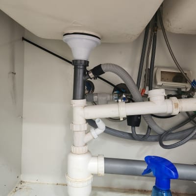 צנרת מתחת לכיור עם בקבוק ריסוס כחול