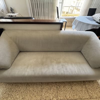 ספה אפורה בחדר עם שולחן וכיסאות ברקע