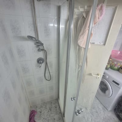מקלחת עם דלת זכוכית ומכונת כביסה