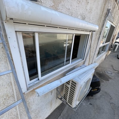 תריסים לבנים מותקנים על חלון קיר חיצוני