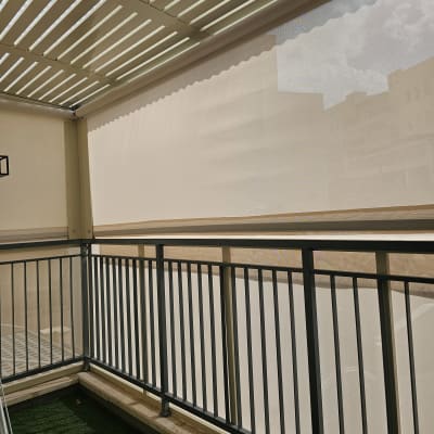 סוכך בד בהיר על מרפסת עם מעקה מתכת