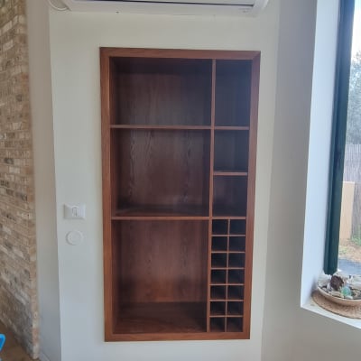 ארון עץ מובנה בקיר עם מדפים ותאים
