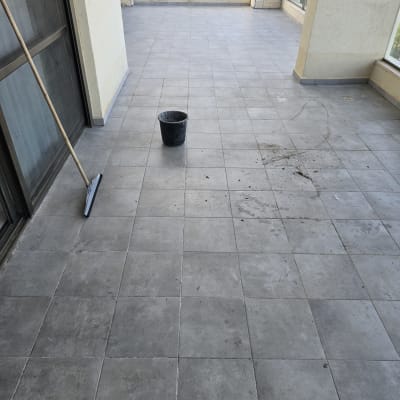 מרפסת עם דלי ומגב על רצפת אריחים אפורה