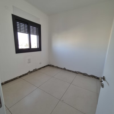 חדר ריק עם רצפת אריחים וקירות לבנים