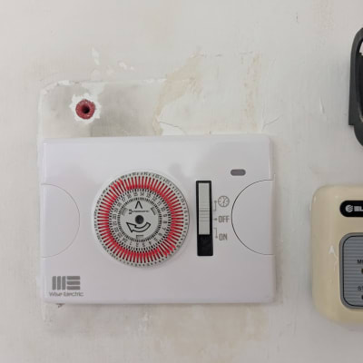 טיימר חשמלי על קיר עם כפתור הפעלה