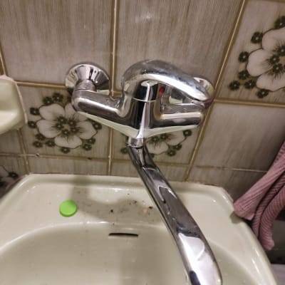 ברז כרום מעל כיור עם לכלוך ופקק ירוק