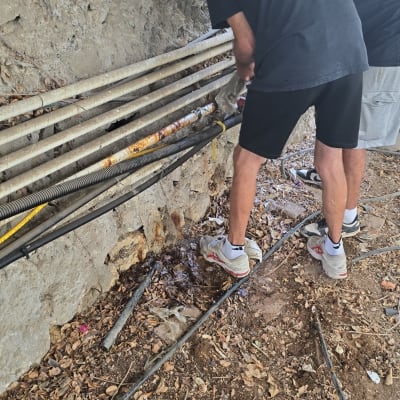 שני אנשים עובדים על צינורות מים עם כלי עבודה