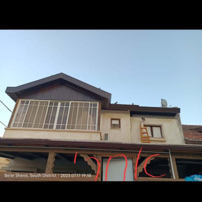 גג עם אנטנה וסולם על קיר הבית