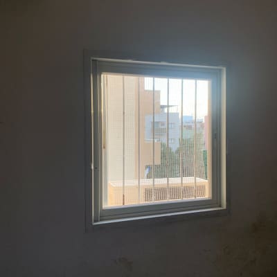 חלון עם סורגי מתכת וקיר חיצוני נראה