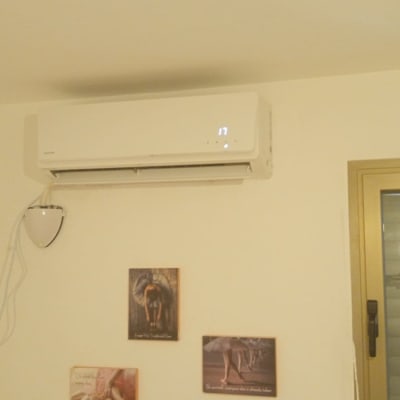 מזגן מותקן על קיר בחדר עם תמונות קטנות