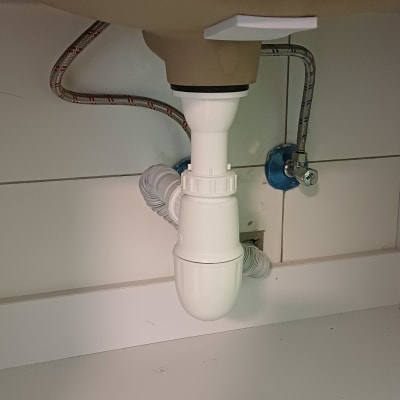 צנרת מתחת לכיור עם חיבורים וצינורות