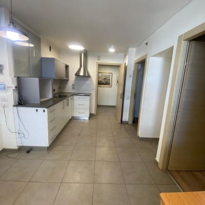 מטבח ריק עם ארונות לבנים ומכסה נירוסטה