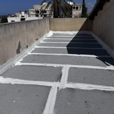 איטום גג עם חומר לבן בין לוחות בטון אפורים