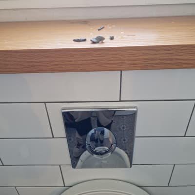 לחצן הדחה בשירותים עם שאריות חומר על המדף