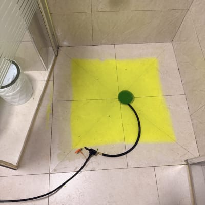 צינור וכלי עבודה על רצפת מקלחת עם צבע צהוב