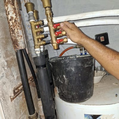 יד מחזיקה ברזים בצנרת עם דלי שחור