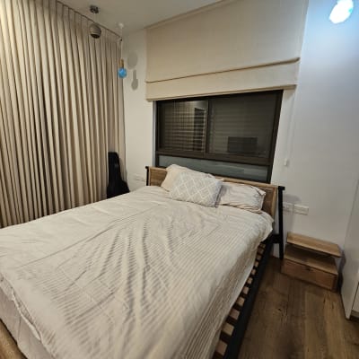 מיטה מסודרת עם מצעים לבנים בחדר שינה