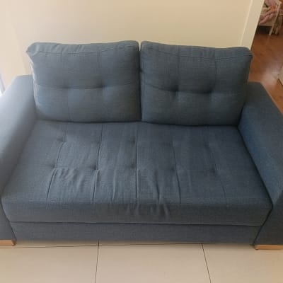 ספה כחולה בחדר מואר על רצפת קרמיקה