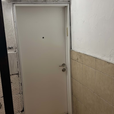 דלת לבנה עם ידית מתכת ומצלמת אבטחה מעל