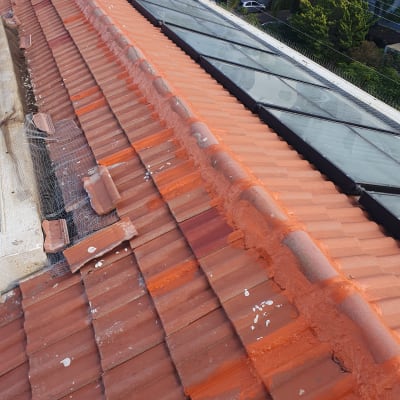 גג רעפים אדום עם תיקונים בצבע כתום