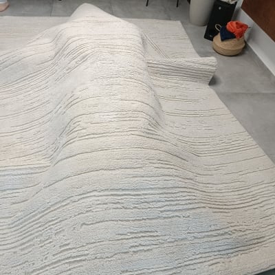 שטיח לבן מקופל על רצפה אפורה