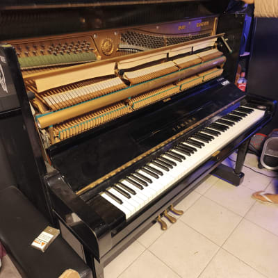 פסנתר עומד פתוח עם יד אדם נוגעת במכסה