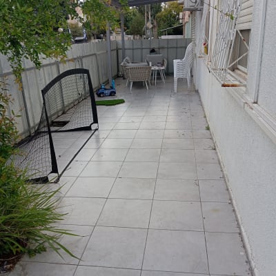 צמחייה ירוקה ליד גדר בחצר מרוצפת