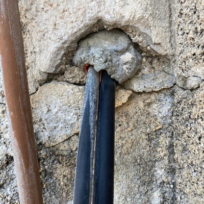 שני כבלים שחורים יוצאים מקיר בטון